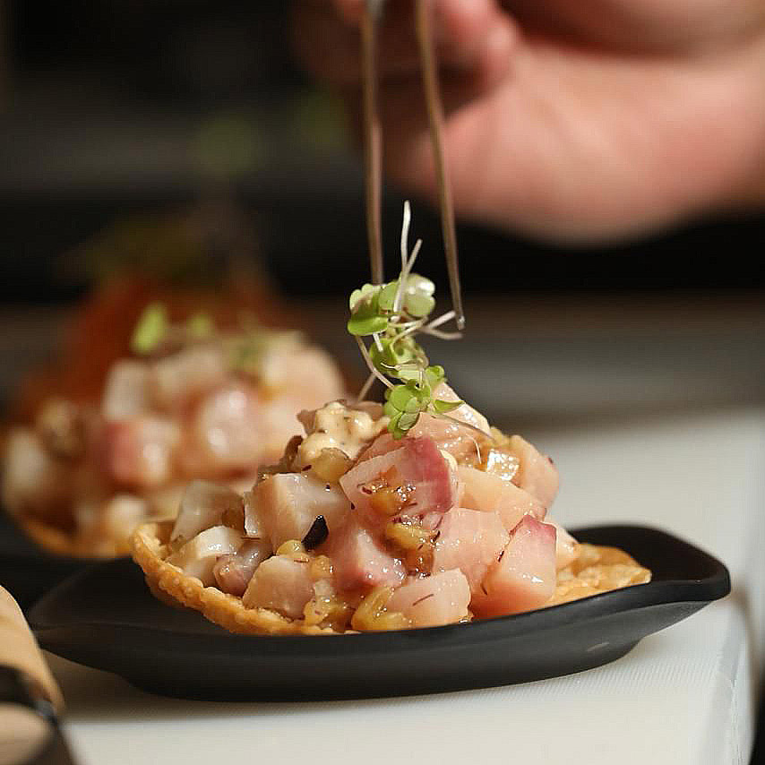 Tostada con pescado en cubos y brotes
