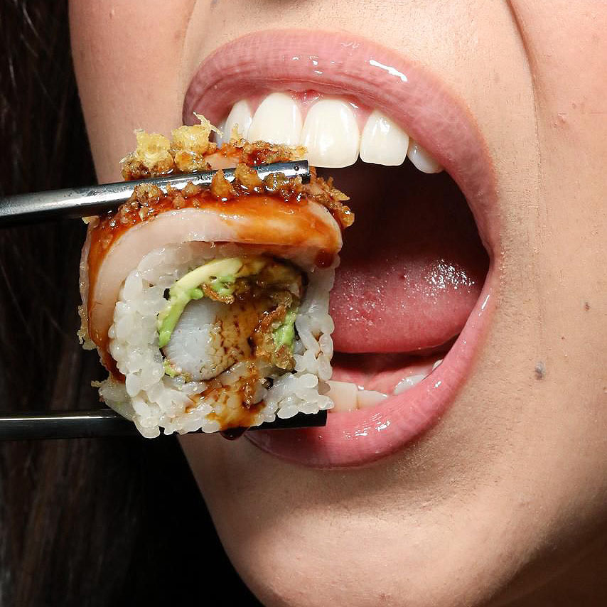 Bocado de sushi frente a la boca de una comensal